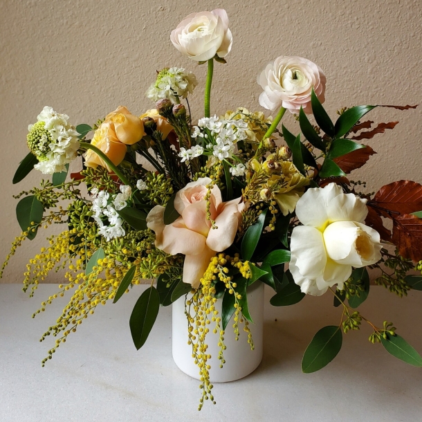 Ava floral arrangement in a white vase with blush and white blooms, yellow accents, and lush greenery