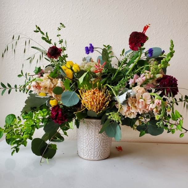Ciri floral arrangement in a textured white vase with mixed blooms and greenery