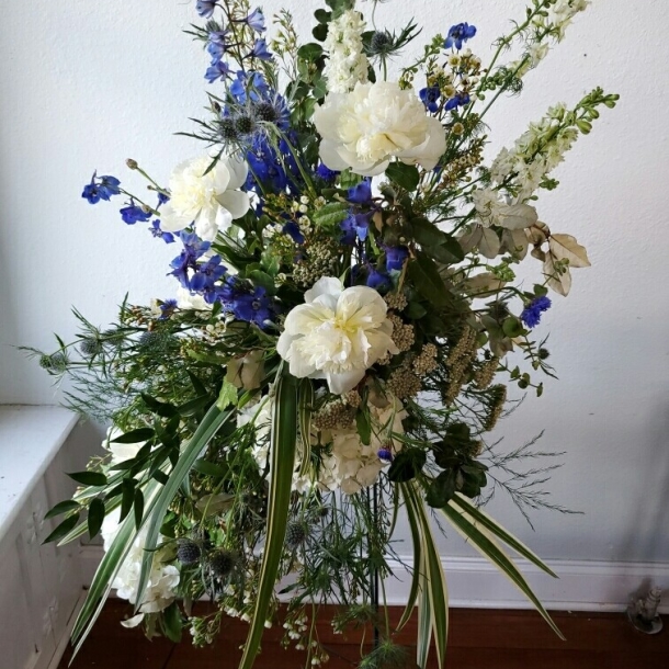 Kind Heart sympathy standing spray with white and blue flowers and greenery