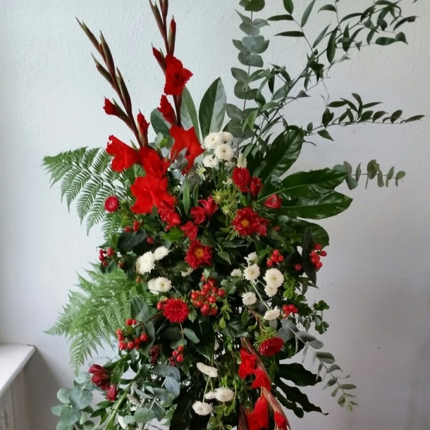 Loved sympathy standing spray with red gladiolus, red berries, white blooms, and lush greenery