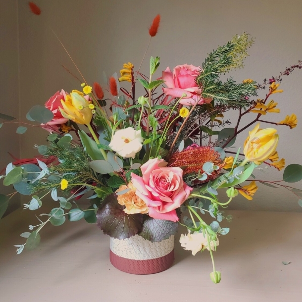 Lumina floral arrangement with pink roses, yellow tulips, and mixed greenery in a textured vase