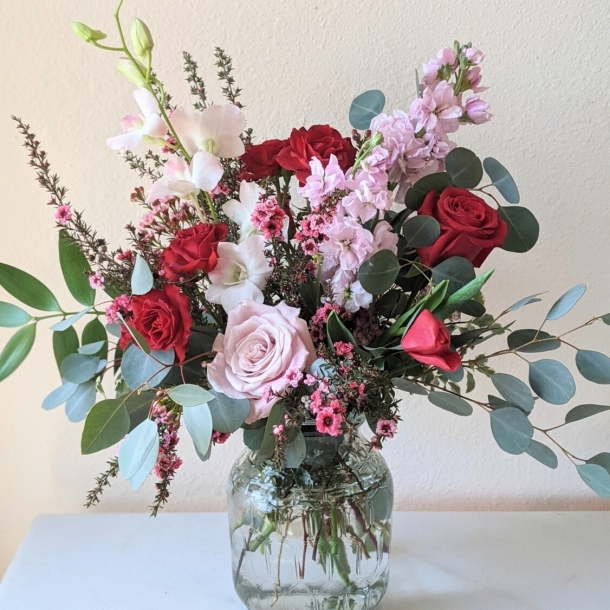 From the Heart mixed floral arrangement with red and blush roses, pink blooms, eucalyptus, and greenery in a glass vase