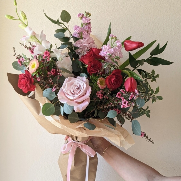 From the Heart mixed wrap bouquet with pink and red roses, tulips, and seasonal flowers in kraft paper wrap
