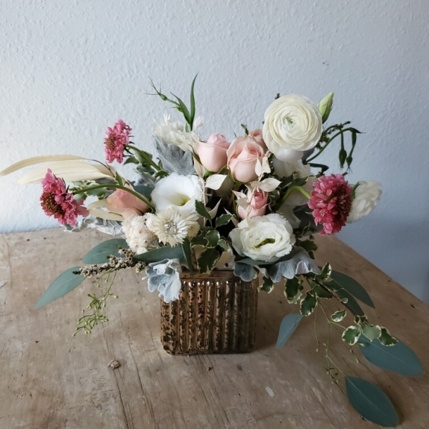 Reverie floral arrangement with blush roses, white ranunculus, and pink blooms in a ribbed glass vase
