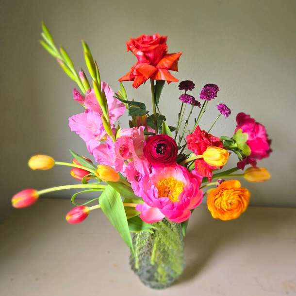 Viola floral arrangement with pink and orange blooms in a textured glass vase